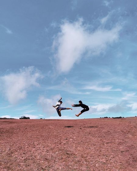 Low angle view of men jumping on land against sky