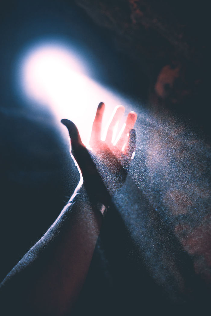Cropped of hand amidst light penetrating through hole