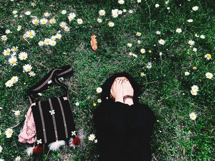 Directly above shot of woman with covered face lying on grassy field