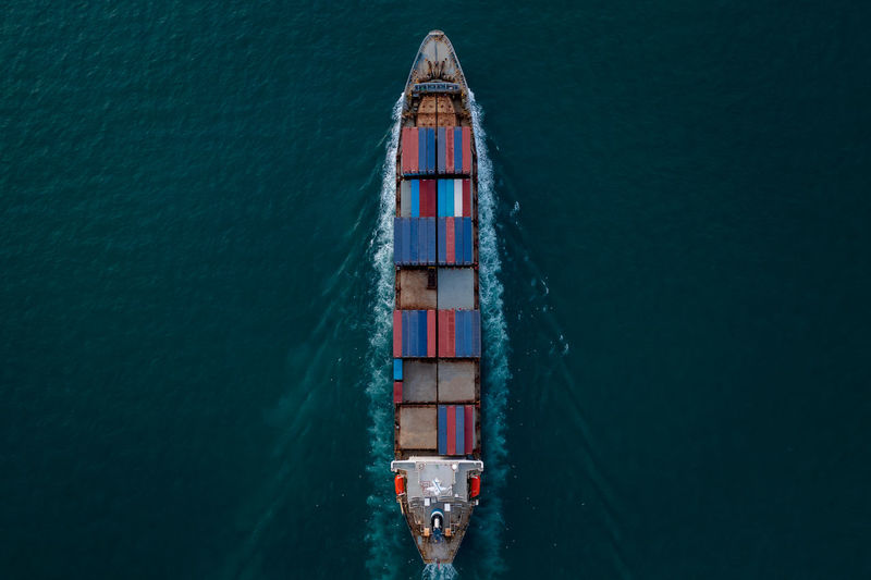 Aerial top view of container ship transporting goods sailing top speed across ocean freight 