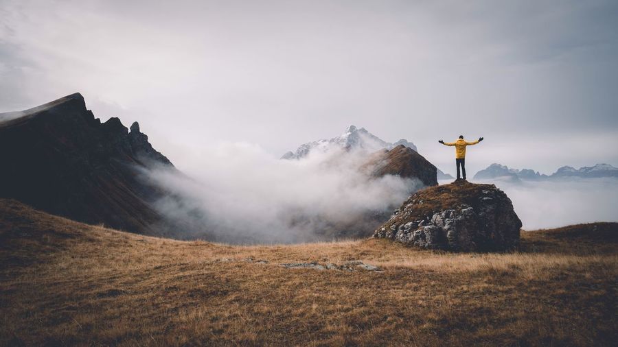 Man standing on rock against mountains during foggy weather
