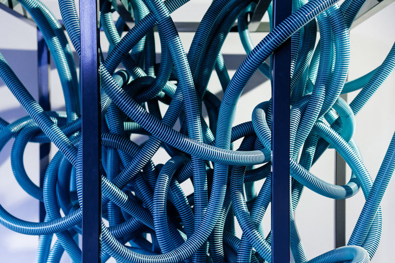 Close-up of blue tangled cables against wall
