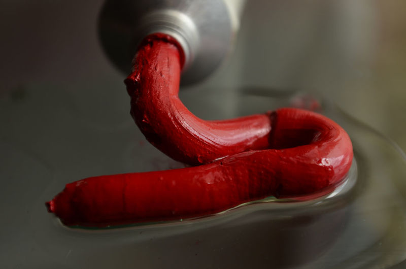 Close-up of red paint spilling from tube