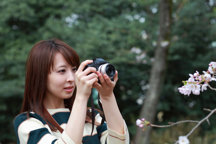 Woman photographing plants with digital camera at park