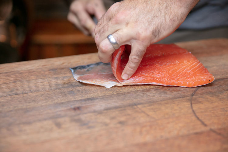 Cropped hand cutting fish on table