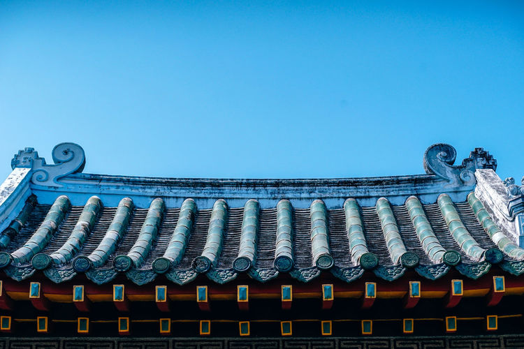 Low angle view of temple roof against clear blue sky