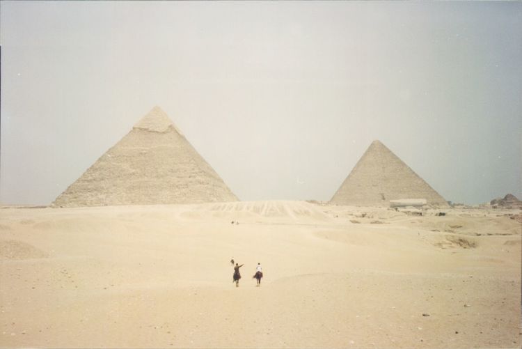 Tourists in front of pyramids against clear sky