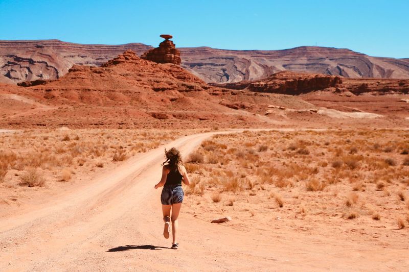 Rear view of teenage girl running at desert