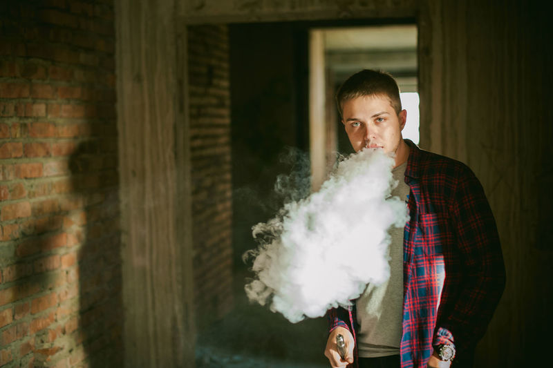 Portrait of young man smoking electronic cigarette
