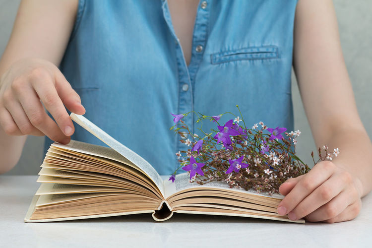 Midsection of woman reading book with flowers