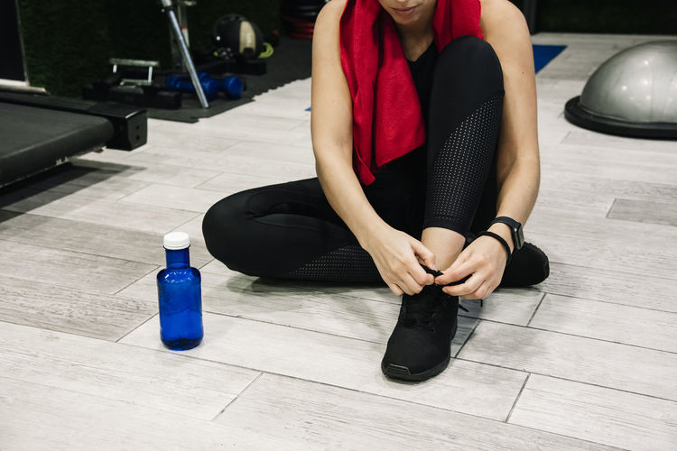 Young woman tying her laces in the gym