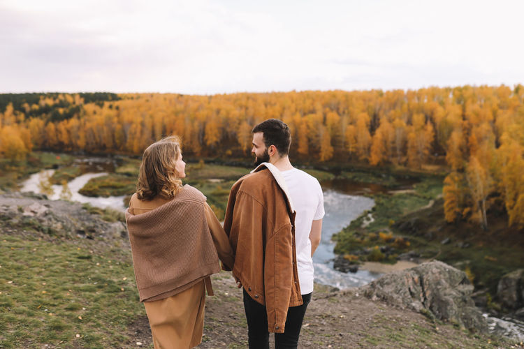 Happy people in love are travel hike in nature in the autumn forest. romantic trip to countryside