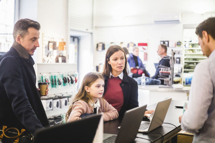 Family shopping for laptop in computer store