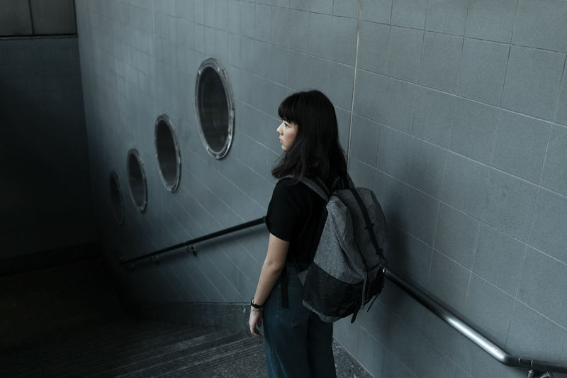 Side view of woman standing against wall