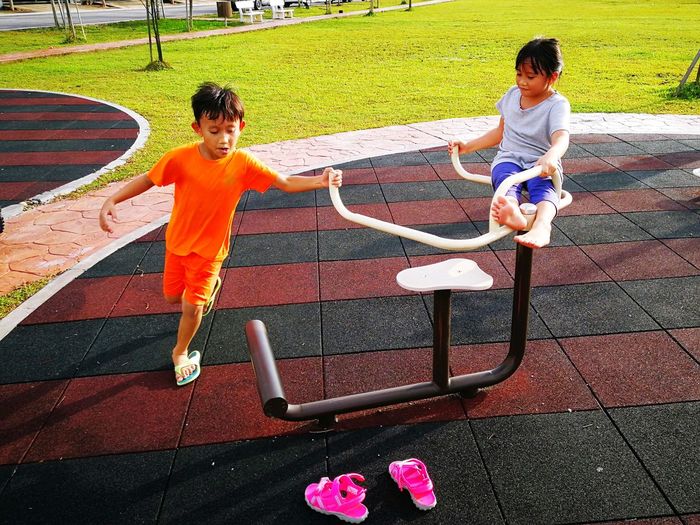 Siblings playing on outdoor play equipment at park