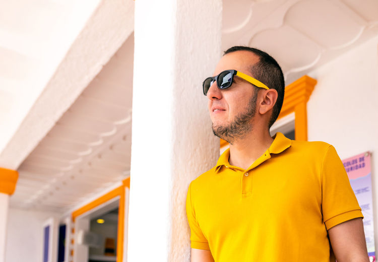 Man wearing sunglasses against wall