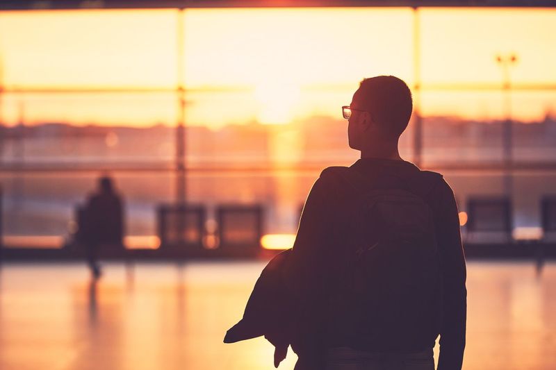 Rear view of man standing at airport during sunset
