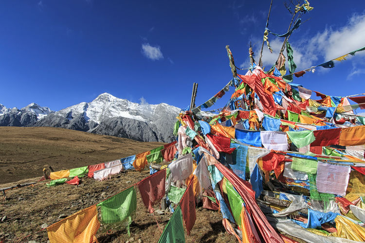 Multi colored praying flags and jade dragon snow mountain against sky