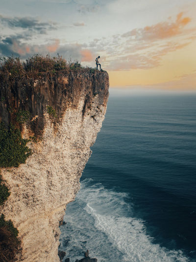 Full length of man standing on cliff against sea and sky