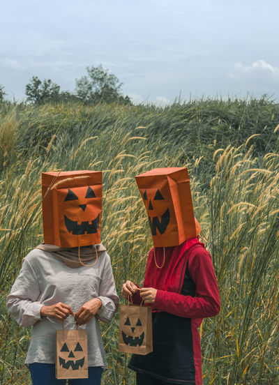 Women wearing mask standing on field against sky