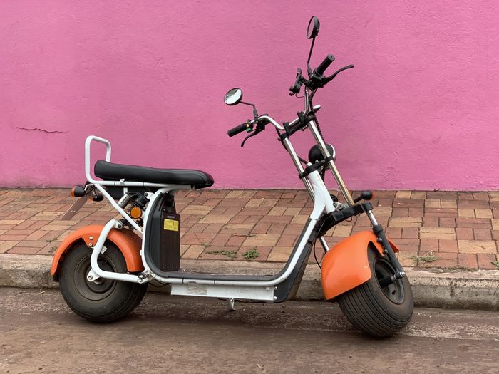 Motor scooter parked against pink wall on santa cruz island galapagos 