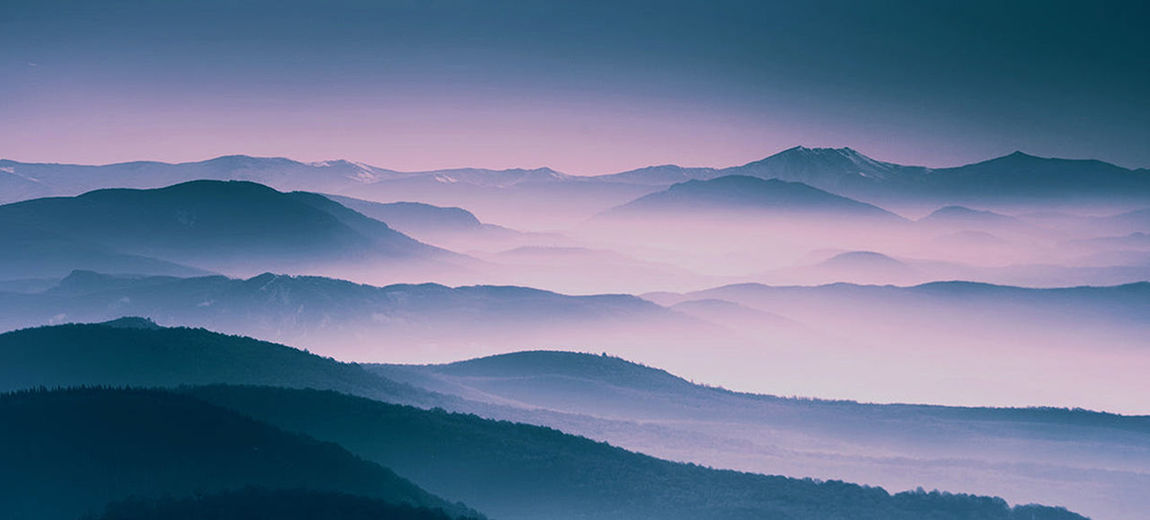 Scenic view of mountains against sky at sunrise