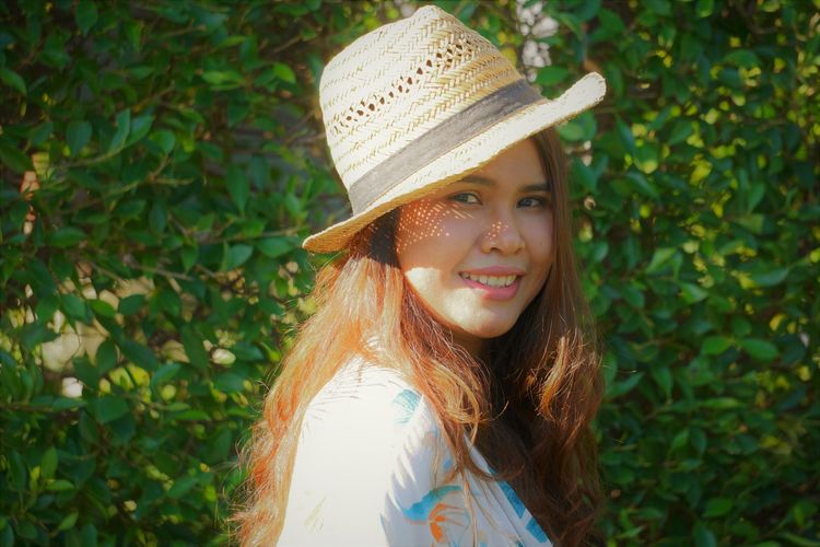 Portrait of smiling woman wearing hat against plants
