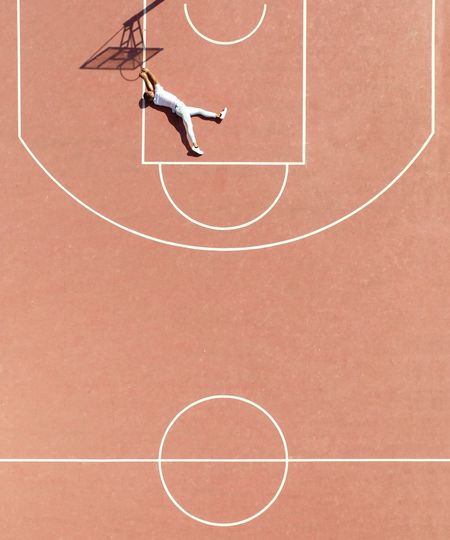 High angle view of man lying on court by basketball hoop shadow