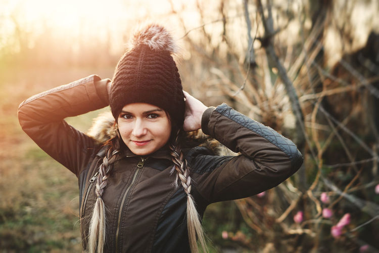 Portrait of young woman in knit hat standing on field