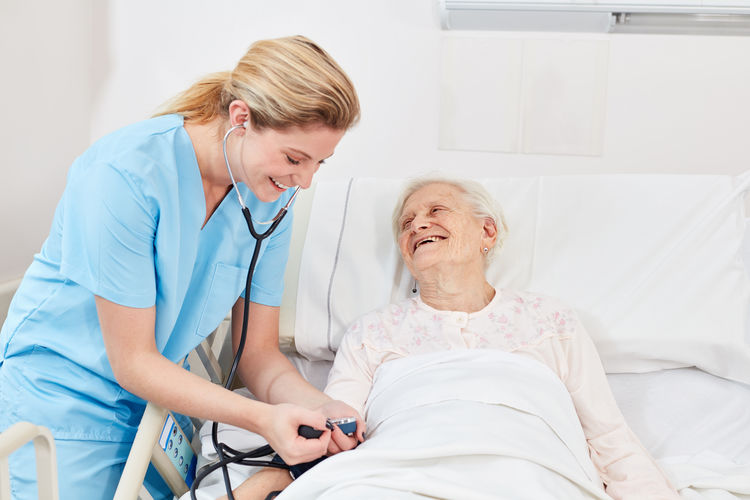 Nurse treating senior female patient at hospital