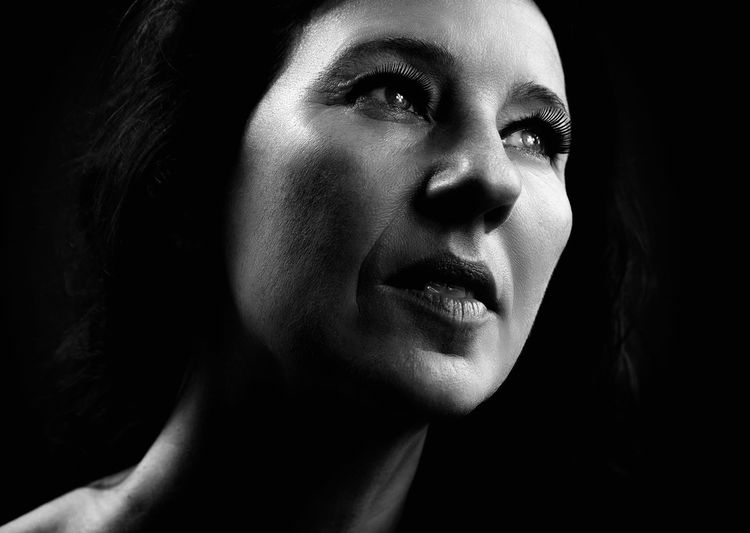 Close-up of thoughtful mature woman against black background