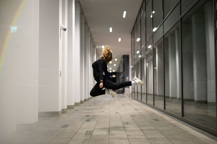 Woman jumping in mid-air at corridor