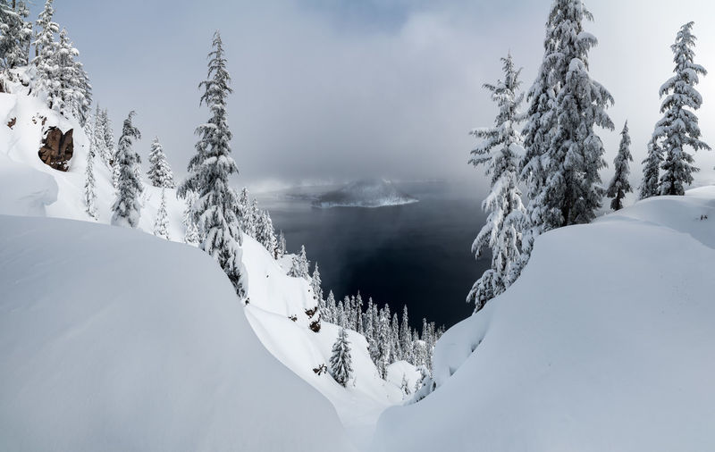 Scenic view of snowcapped mountains by lake against cloudy sky