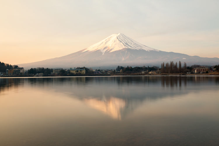 Scenic view of lake and snowcapped mountains against sky during sunset