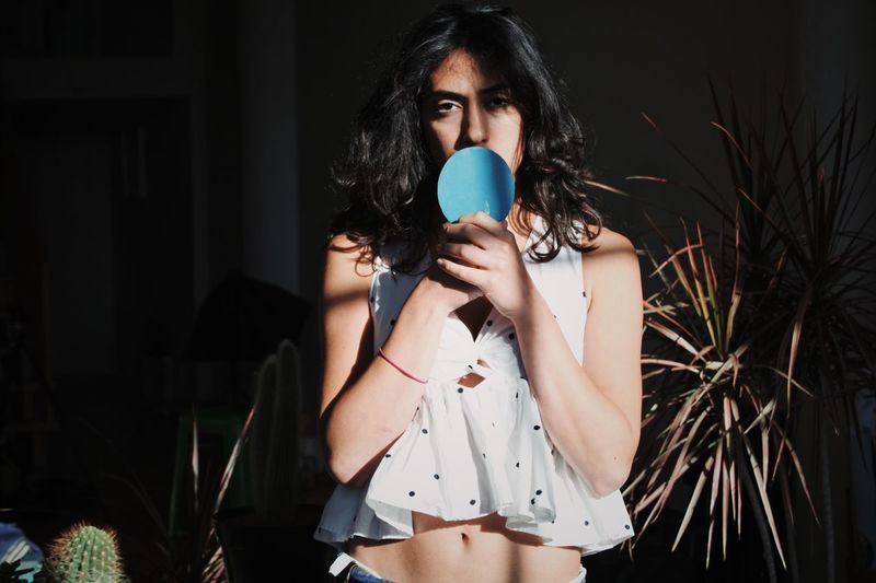 Portrait of young woman holding table tennis racket while standing at home