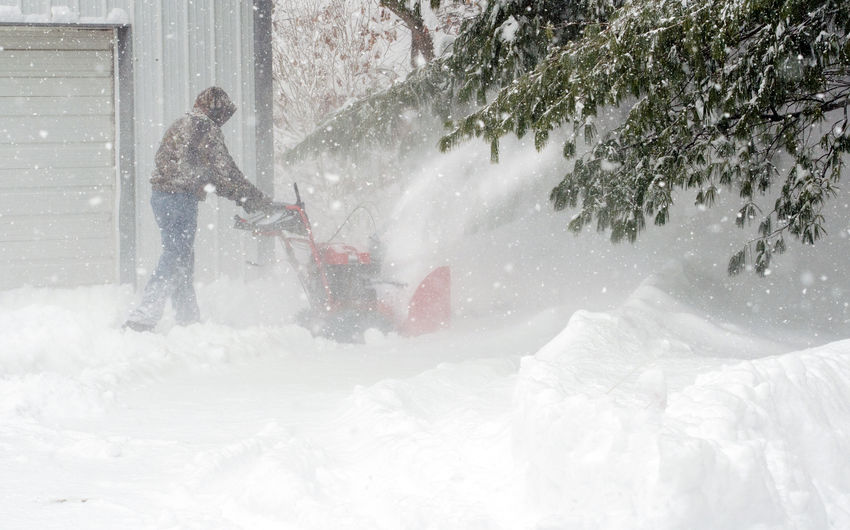 Man clearing snow during a winter storm with a snow blower