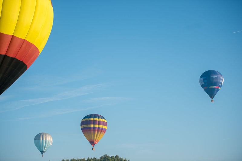 Low angle view of colorful hot air balloons flying against sky
