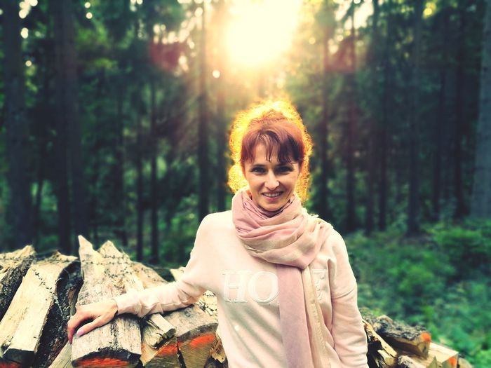 Portrait of smiling woman standing against trees