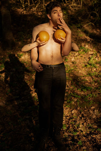 Cropped hand of woman holding fruit over man chest in forest