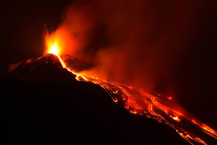Eruption on etna volcano in sicily with great lava explosion from top crater and lava flow at night