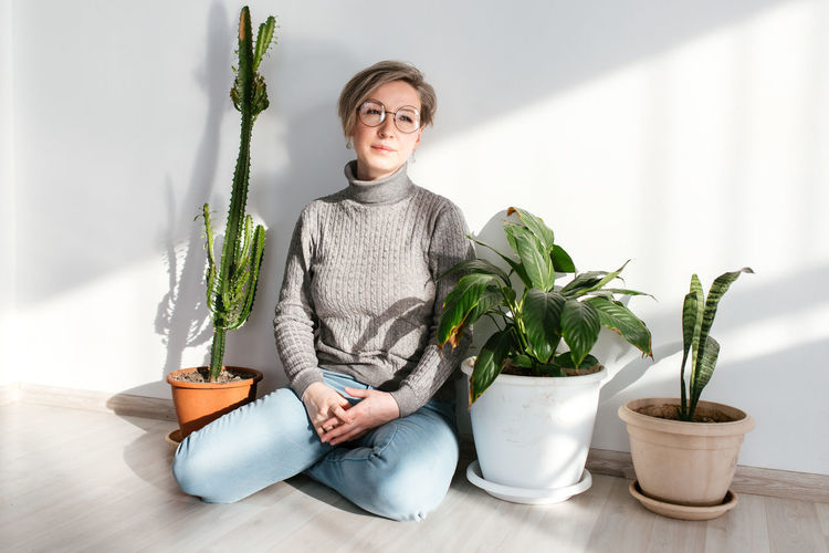 Portrait of young woman sitting on potted plant