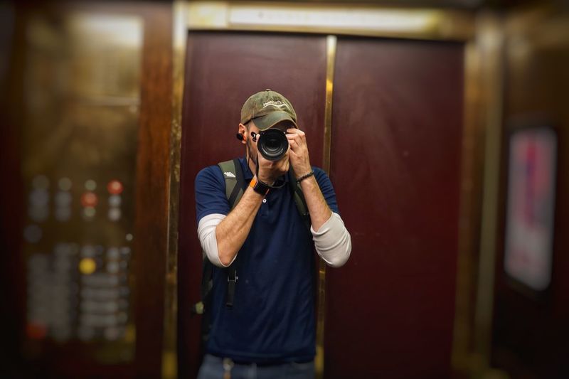 Man photographing while standing against door