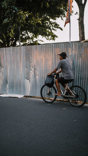 Side view of man riding bicycle on street