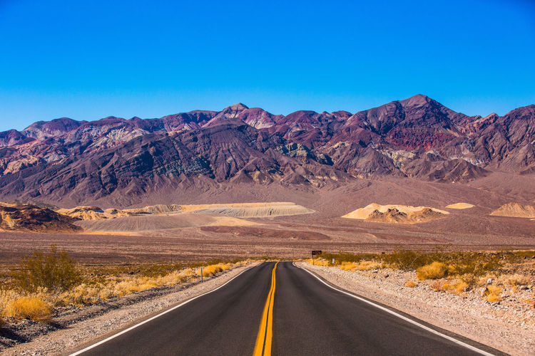 Road leading towards mountains against sky