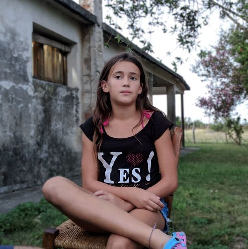 Thoughtful girl looking away while sitting on chair