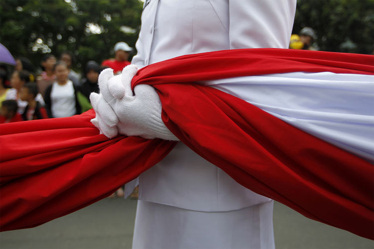 Midsection of woman holding indonesian flag during parade