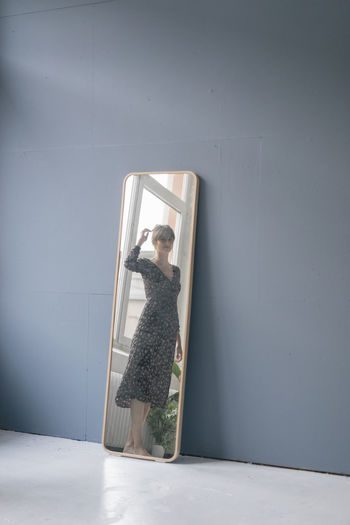 Young woman in vintage dress looking into mirror
