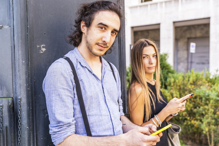 Portrait of couple using smart phone while standing outdoors