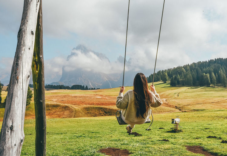 Rear view of woman on swing against mountains