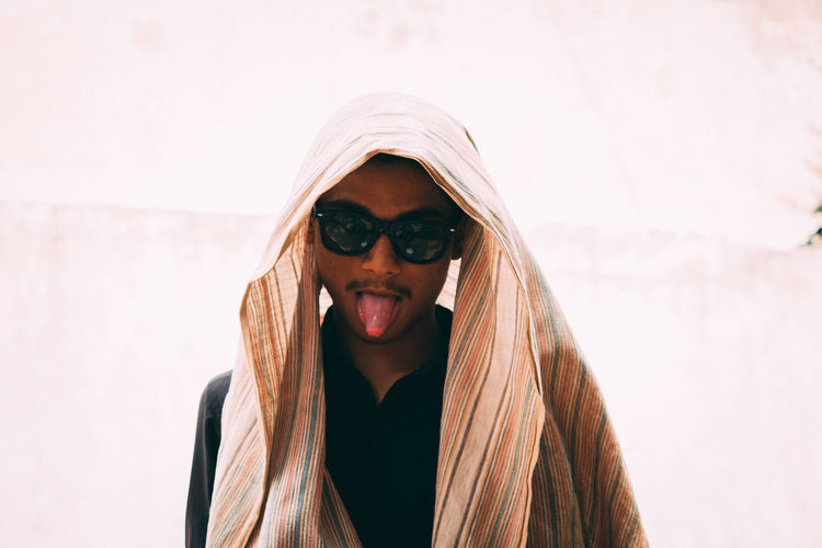 Portrait of teenage boy wearing sunglasses sticking out tongue outdoors